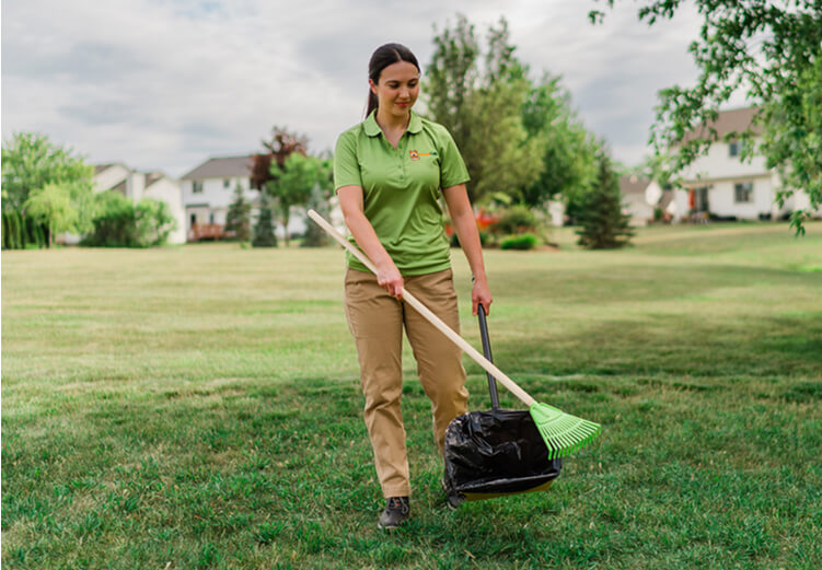 A uniformed DoodyCalls technician cleaning a grassy property